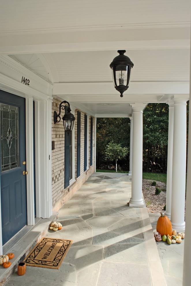 Cette image montre un porche d'entrée de maison avant traditionnel de taille moyenne avec des pavés en pierre naturelle et une extension de toiture.