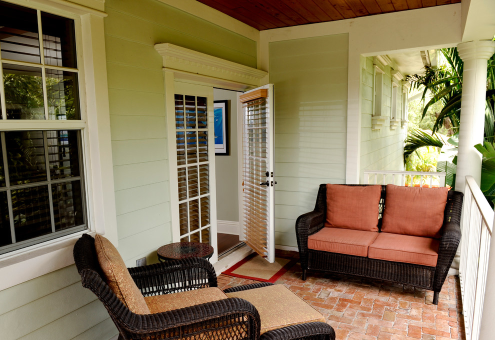 This is an example of a world-inspired front veranda in Miami with brick paving.