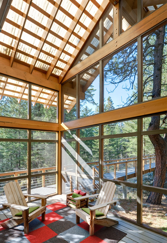 Réalisation d'un grand porche d'entrée de maison design avec une moustiquaire, une terrasse en bois et une extension de toiture.