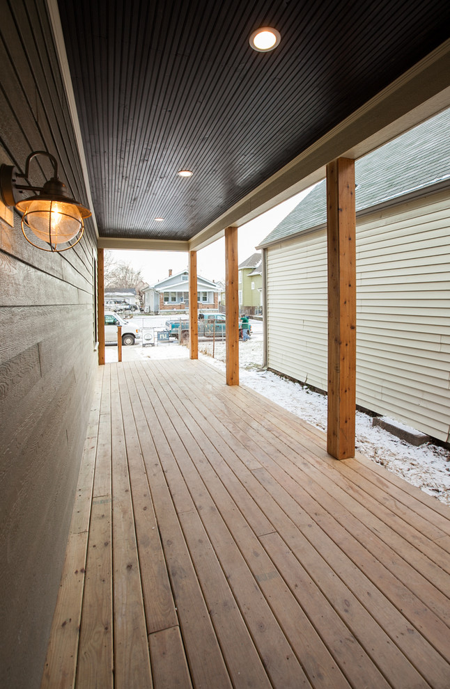 Réalisation d'un grand porche d'entrée de maison avant bohème avec une terrasse en bois et une extension de toiture.