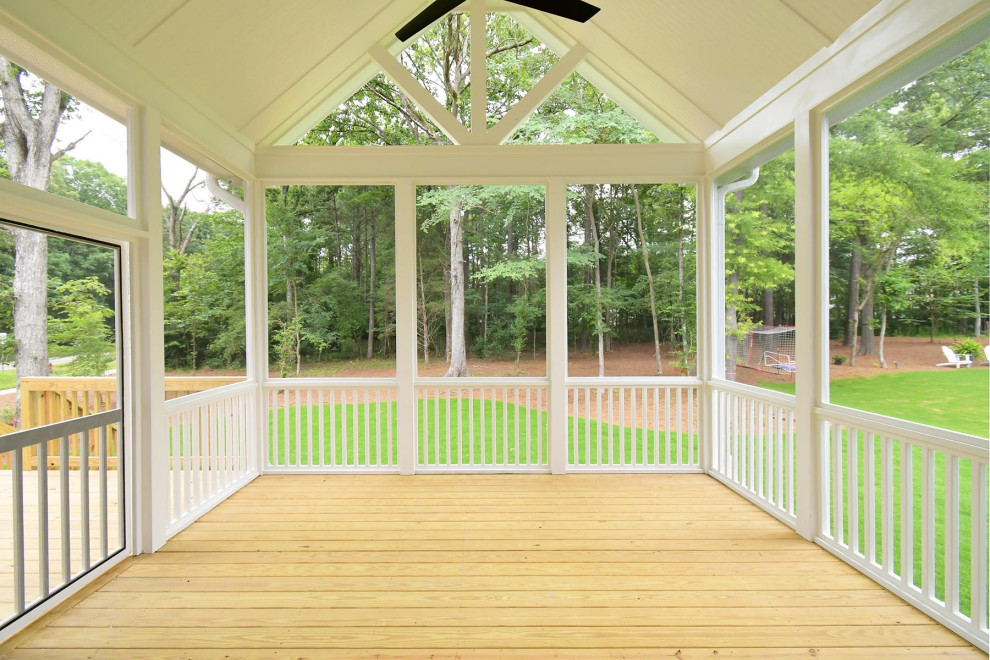 Cette photo montre un grand porche d'entrée de maison arrière chic avec une moustiquaire, une terrasse en bois et une extension de toiture.