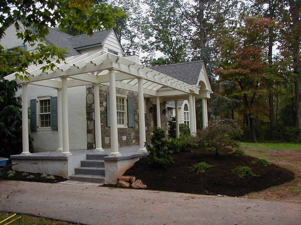 Inspiration för en stor amerikansk veranda framför huset, med stämplad betong och en pergola