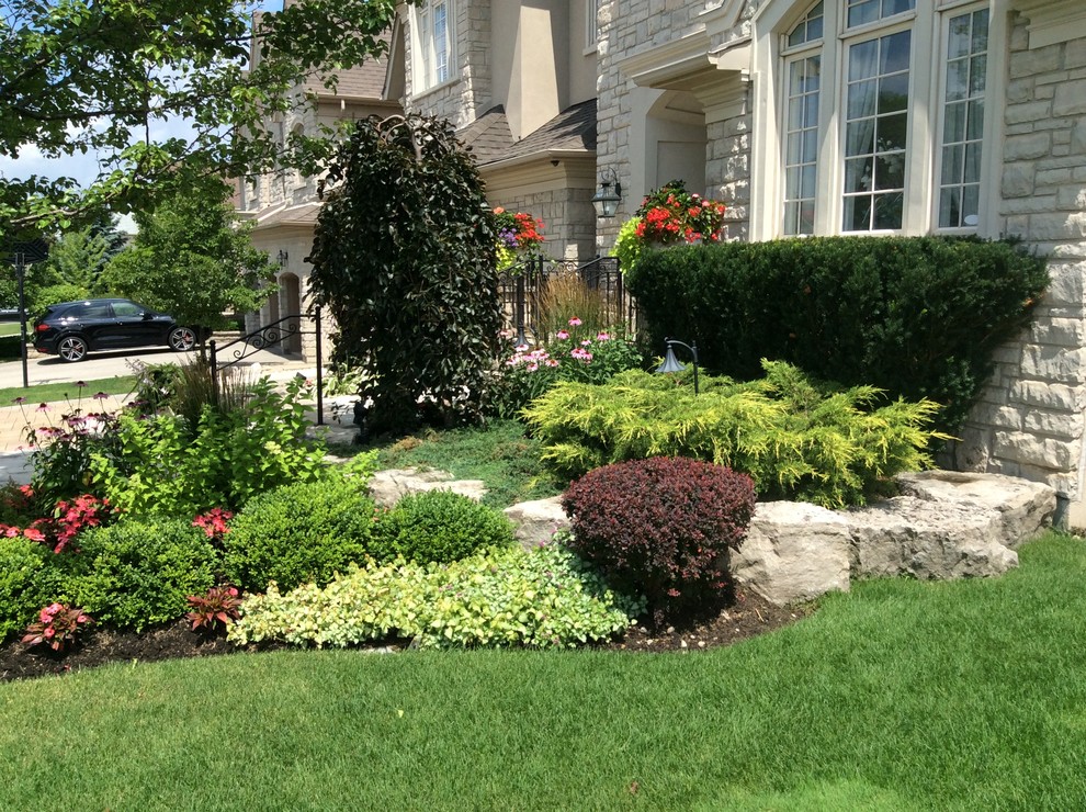 Photo of a mid-sized traditional front yard stone landscaping in Toronto.