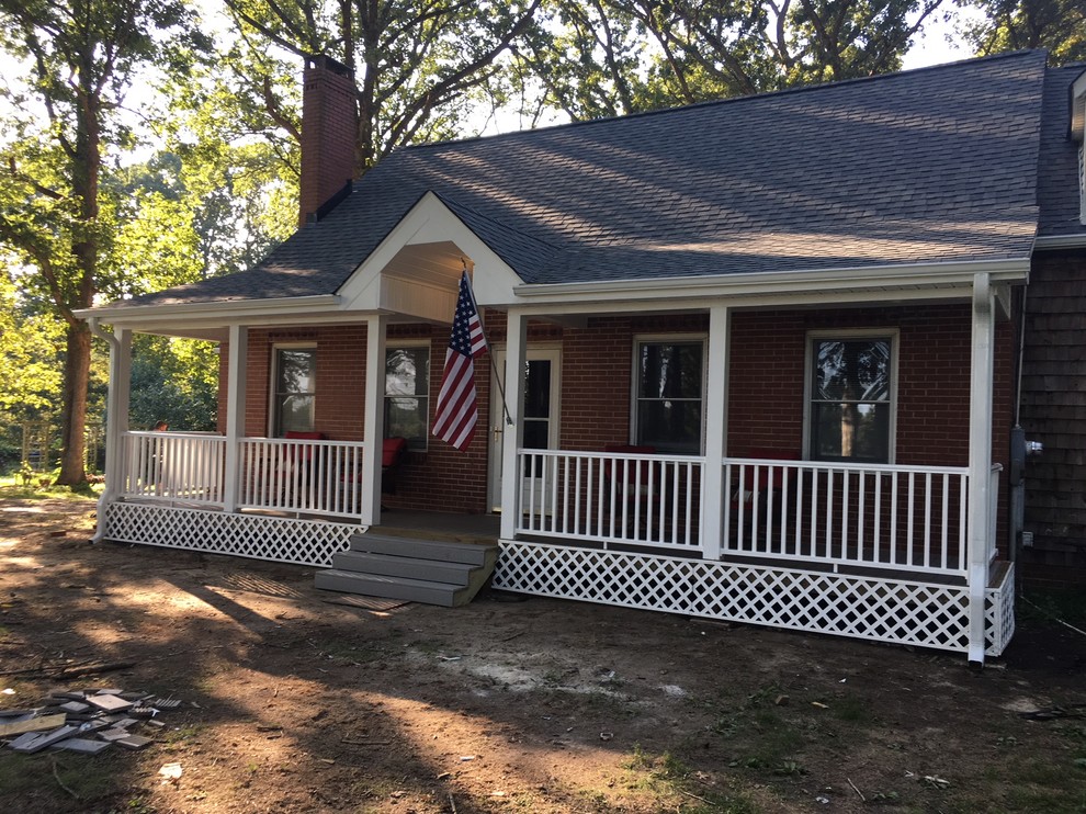 This is an example of a mid-sized country front porch design in Raleigh with a roof extension.