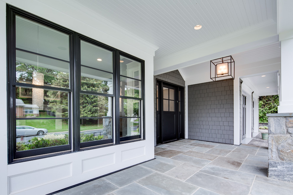 Réalisation d'un grand porche d'entrée de maison avant design avec des pavés en pierre naturelle et une extension de toiture.
