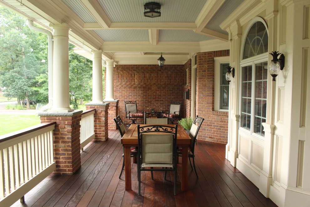 This is an example of a large traditional front porch design in New York with decking and a roof extension.