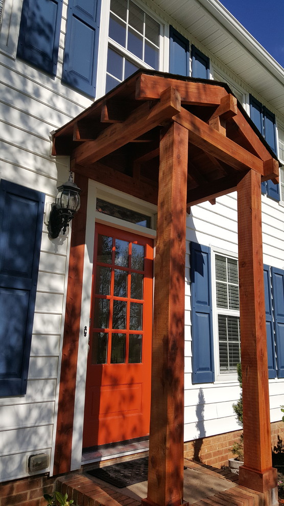 Exempel på en liten amerikansk veranda framför huset, med marksten i tegel