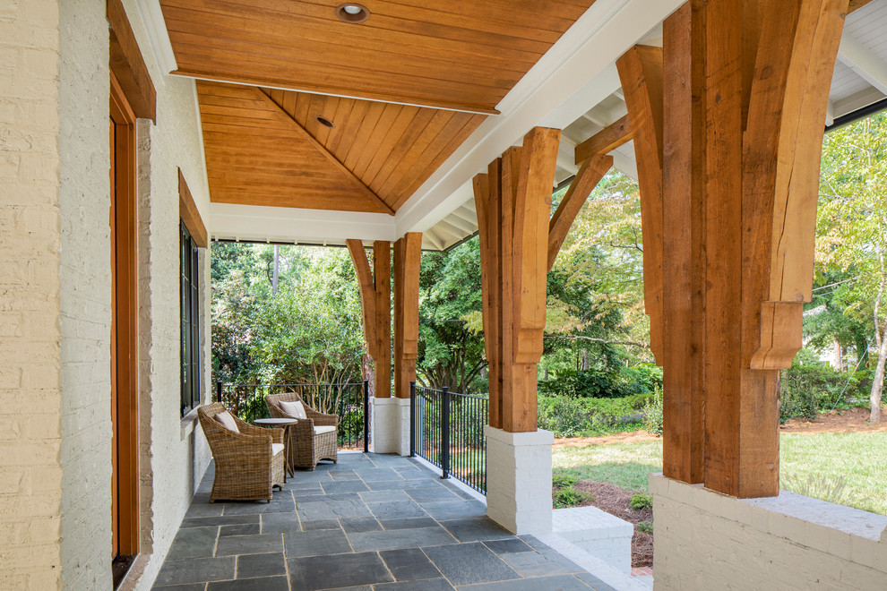 Idéer för att renovera en mellanstor vintage veranda framför huset, med naturstensplattor och takförlängning