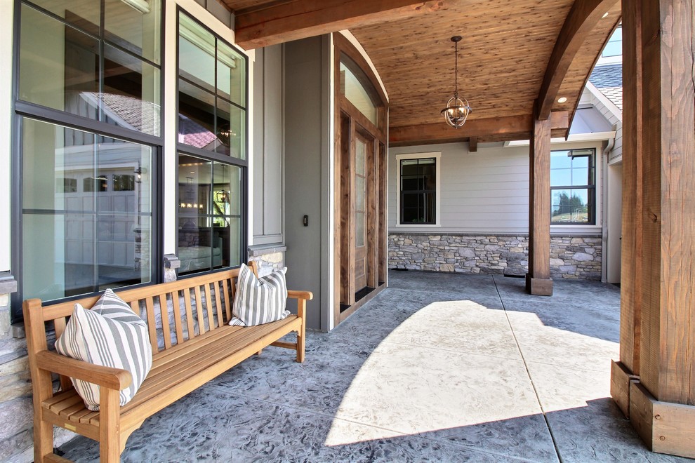 Exemple d'un très grand porche d'entrée de maison arrière craftsman avec du béton estampé et une extension de toiture.