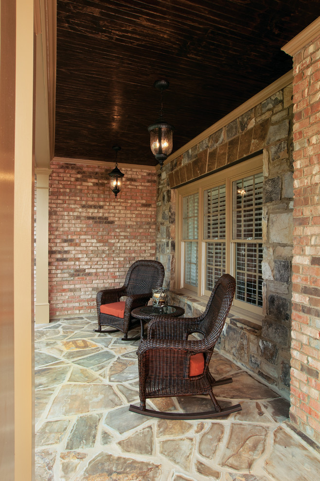 This is an example of a mid-sized traditional stone front porch design in Atlanta with a roof extension.