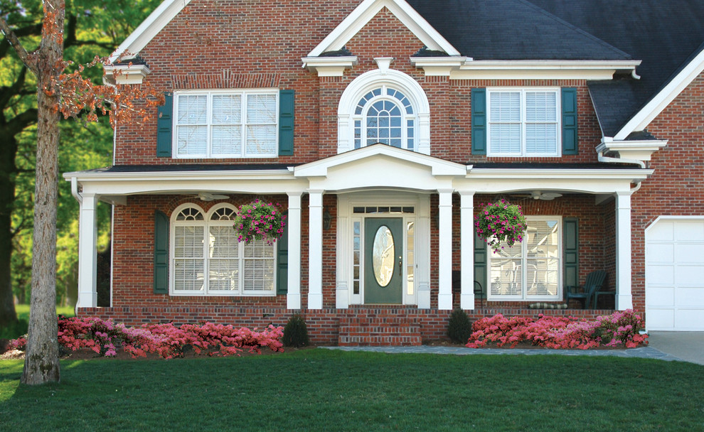 This is an example of a large transitional stone front porch design in Atlanta with a roof extension.