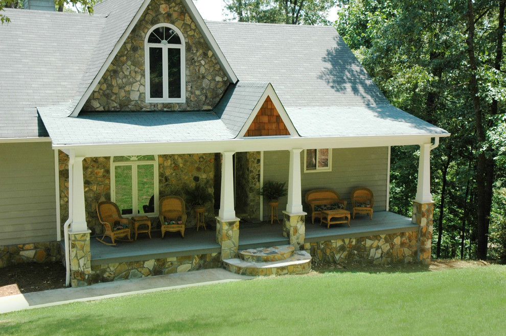 Cette photo montre un très grand porche d'entrée de maison avant craftsman avec une extension de toiture et une terrasse en bois.