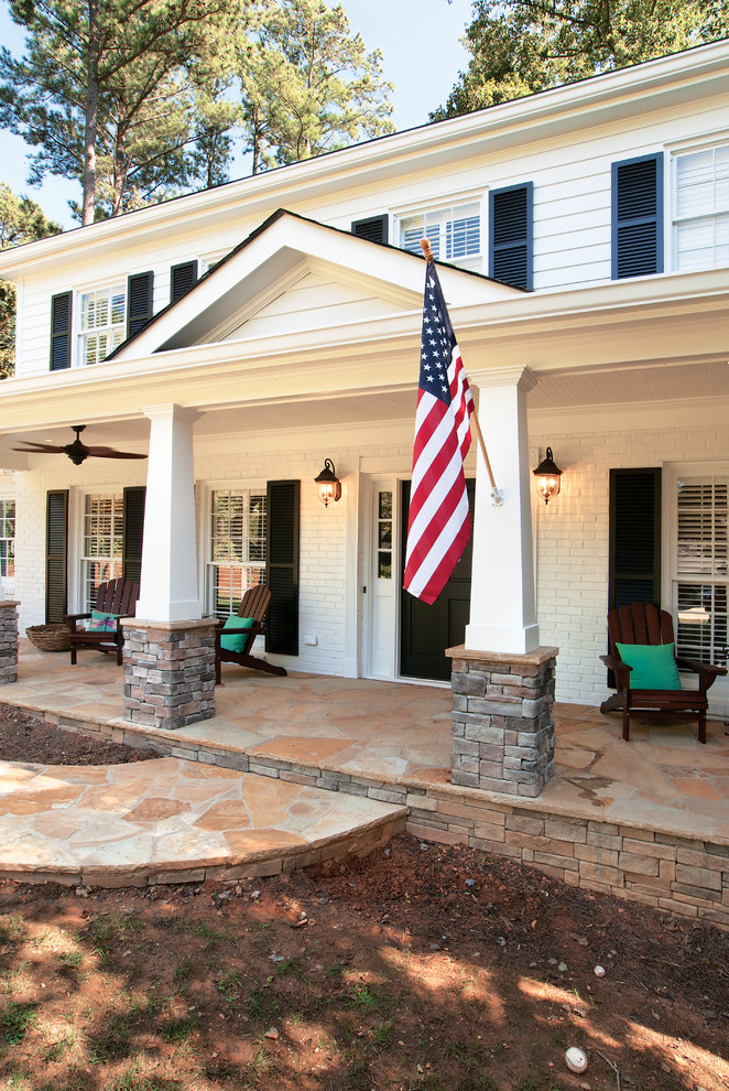 Foto di un grande portico american style davanti casa con pavimentazioni in pietra naturale e un tetto a sbalzo
