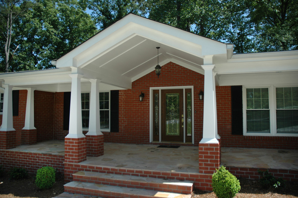 Inspiration pour un grand porche d'entrée de maison avant traditionnel avec une extension de toiture et des pavés en brique.