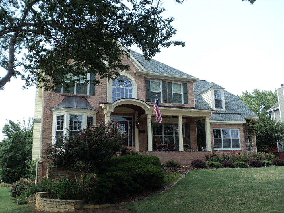 Large transitional stone front porch photo in Atlanta with a roof extension