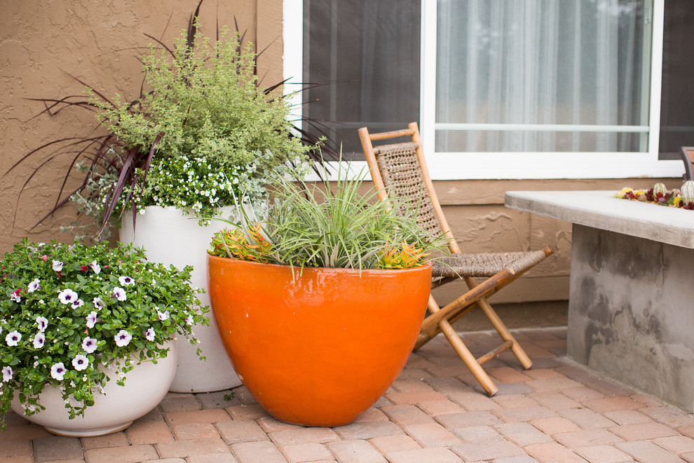 Immagine di un piccolo portico mediterraneo davanti casa con un giardino in vaso e pavimentazioni in mattoni