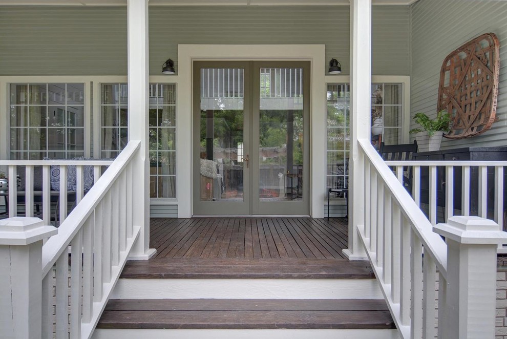 Foto på en mellanstor lantlig veranda framför huset, med trädäck och takförlängning