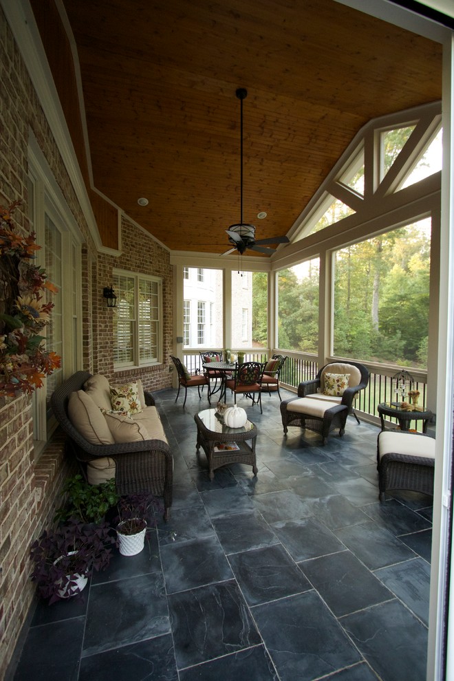 Exempel på en mellanstor klassisk innätad veranda på baksidan av huset, med naturstensplattor