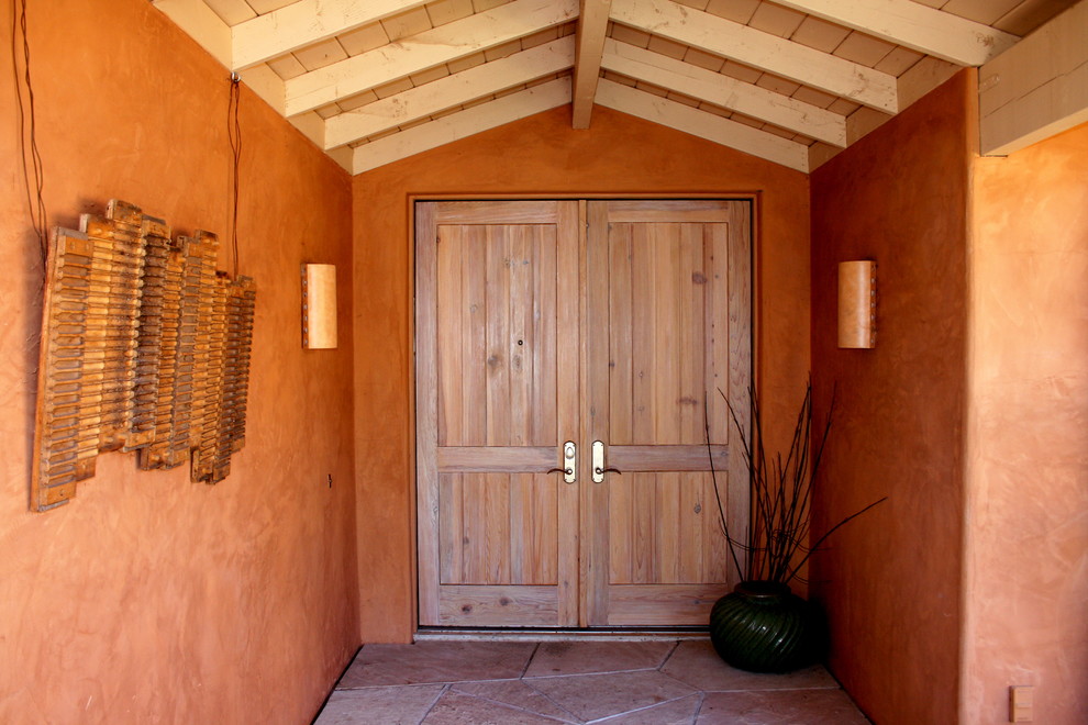 Aménagement d'un porche d'entrée de maison avant méditerranéen avec des pavés en pierre naturelle et une extension de toiture.
