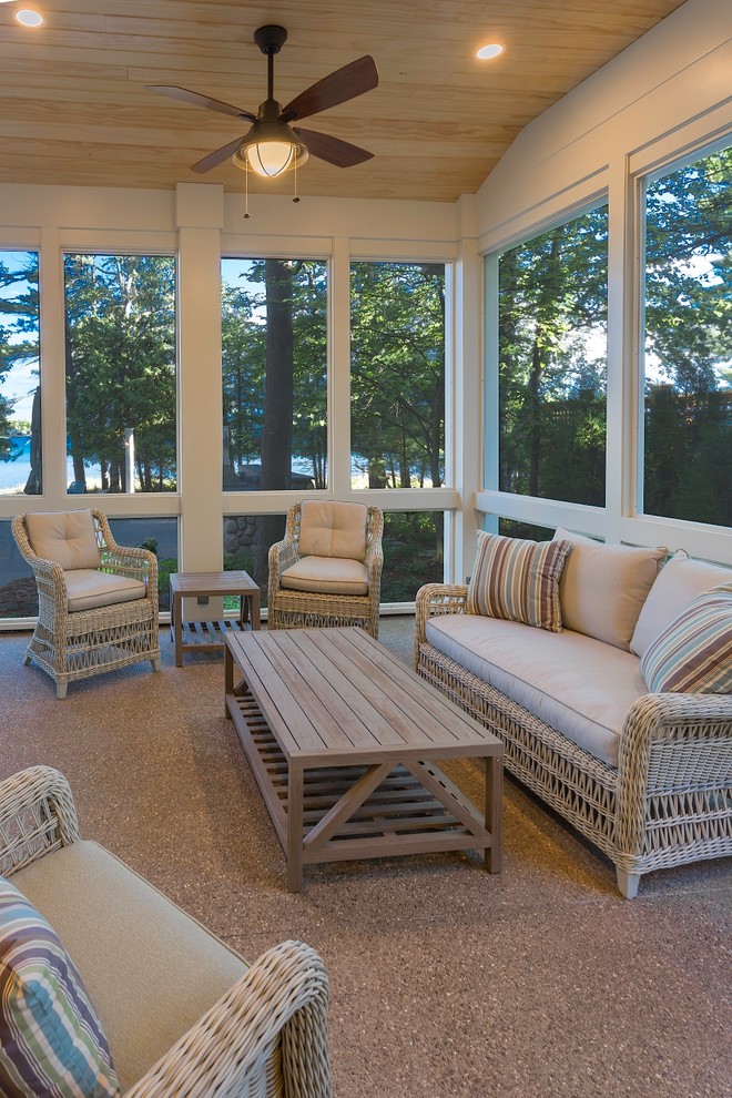 This is an example of a large coastal stamped concrete screened-in side porch design in Other with a roof extension.
