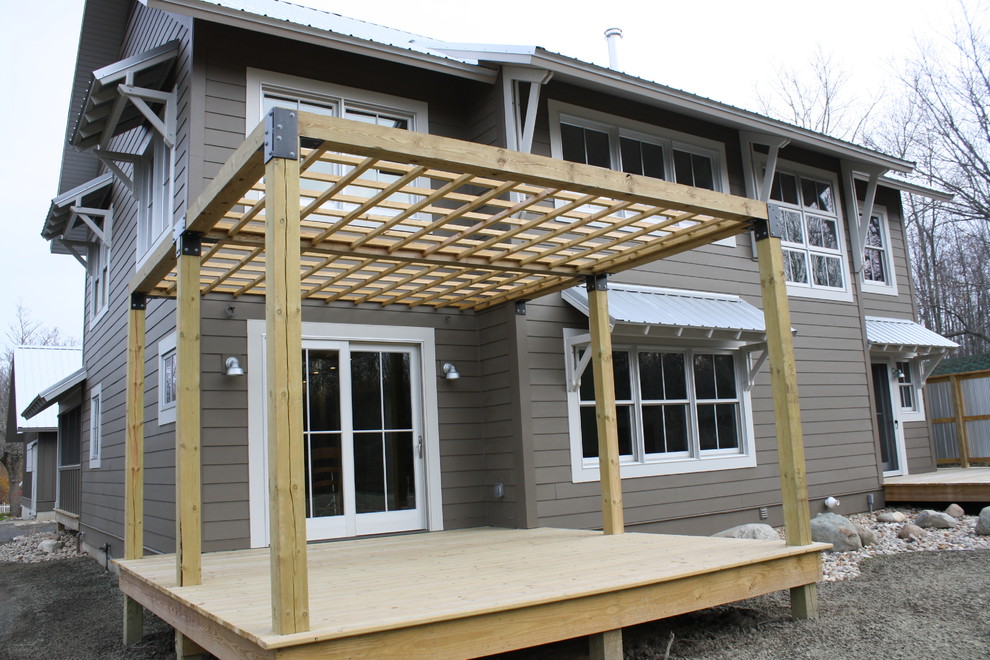 Cette photo montre un porche d'entrée de maison tendance avec une terrasse en bois et une pergola.