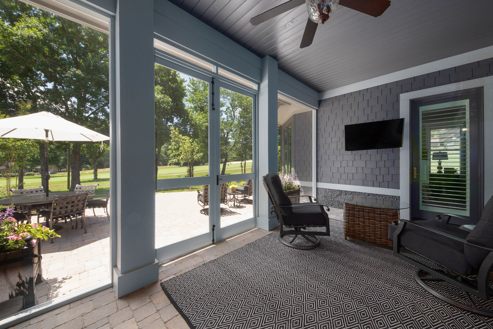 Idée de décoration pour un grand porche d'entrée de maison arrière craftsman avec une moustiquaire, des pavés en béton et une extension de toiture.
