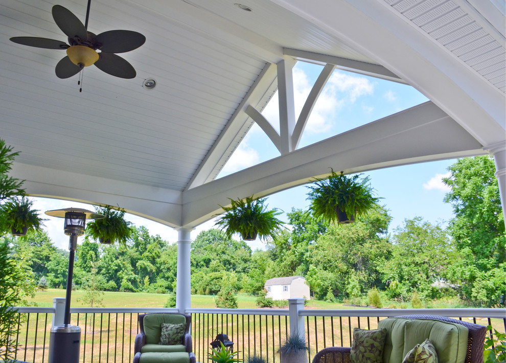 Cette photo montre un grand porche d'entrée de maison arrière moderne avec un foyer extérieur et une extension de toiture.