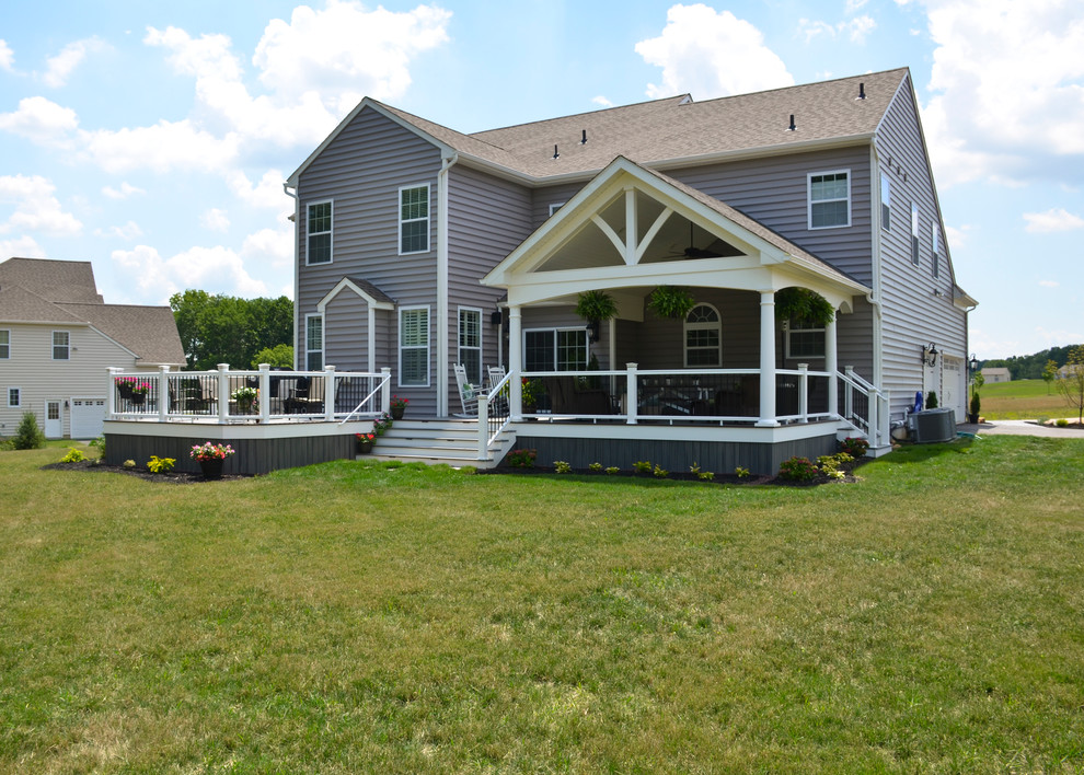 Cette photo montre un grand porche d'entrée de maison arrière moderne avec un foyer extérieur et une extension de toiture.