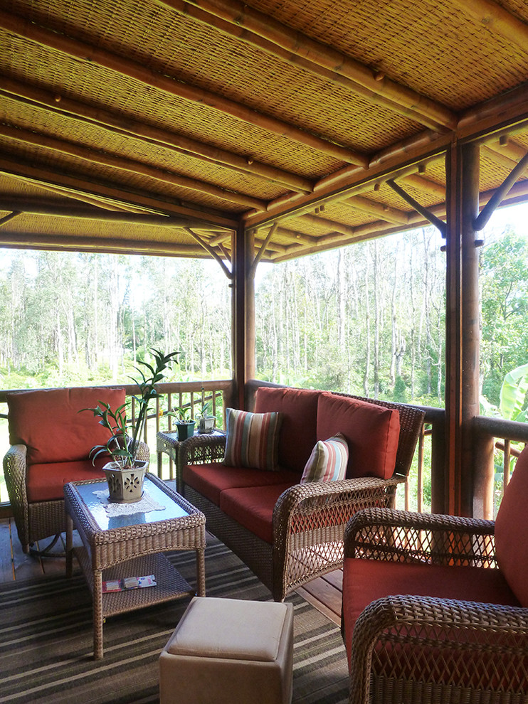 Cette photo montre un porche d'entrée de maison latéral exotique avec une moustiquaire, une terrasse en bois et une extension de toiture.