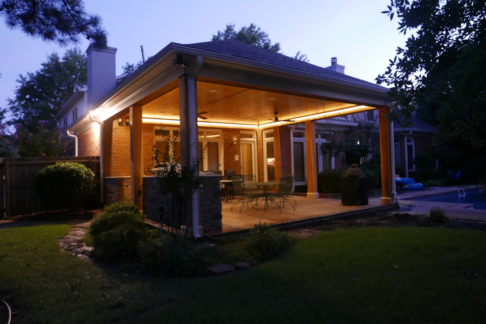 Große, Überdachte Klassische Veranda hinter dem Haus mit Outdoor-Küche und Stempelbeton in Sonstige
