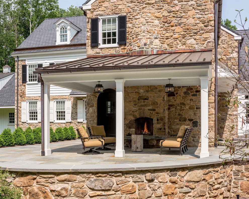 Elegant stone back porch photo in Philadelphia with a roof extension