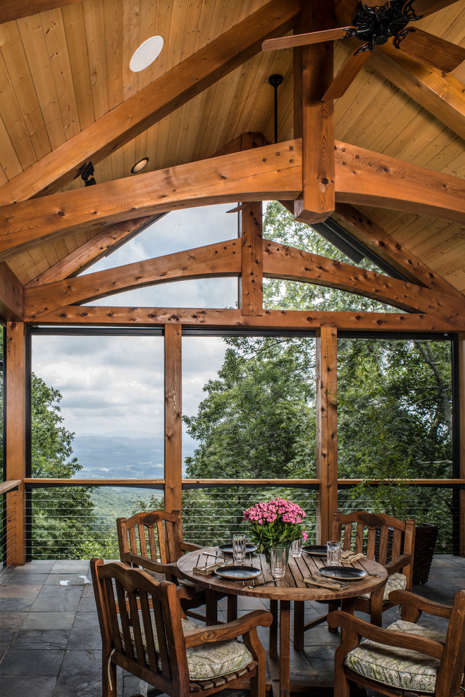 Cette image montre un grand porche d'entrée de maison chalet avec une cuisine d'été, des pavés en pierre naturelle et une extension de toiture.