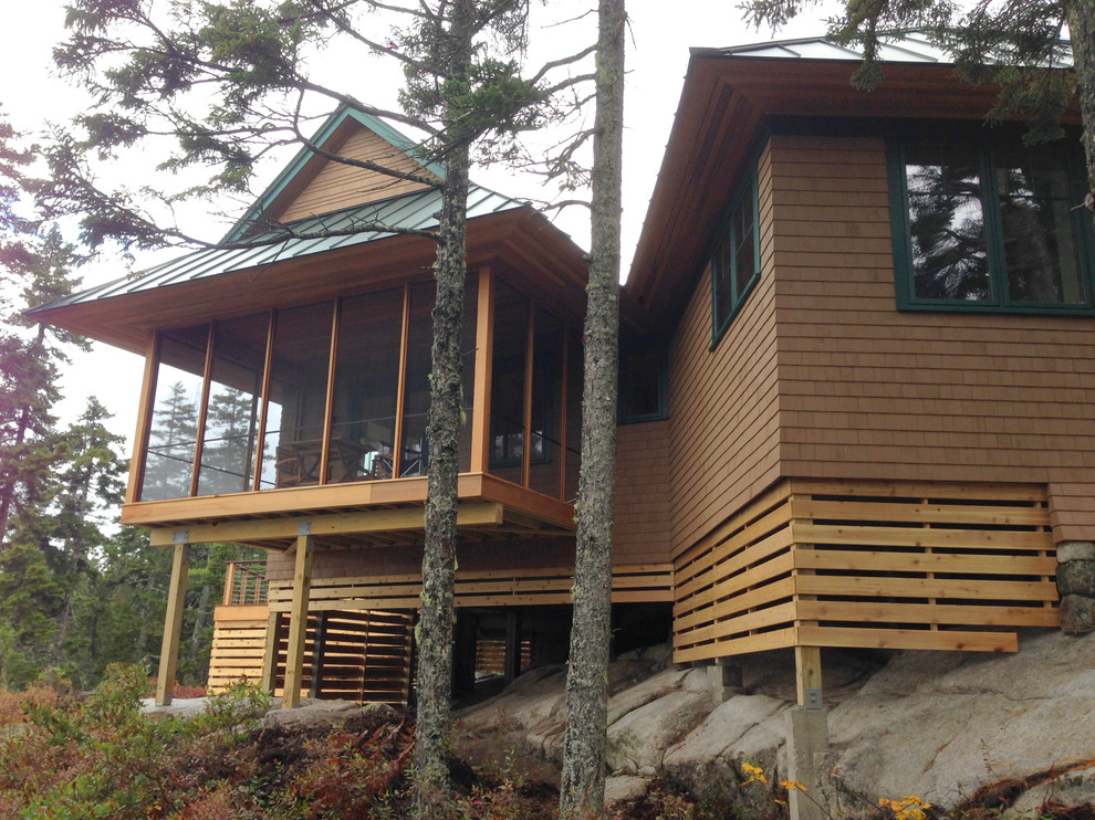 Exemple d'un porche d'entrée de maison arrière montagne avec une moustiquaire, une terrasse en bois et une extension de toiture.
