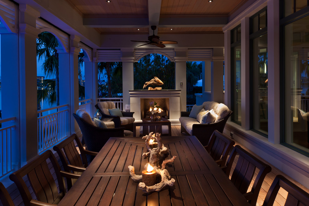 This is an example of a large tropical back porch design in Miami with a fire pit.