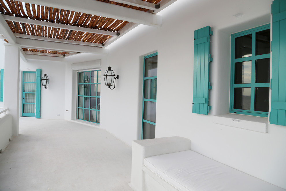 Idée de décoration pour un porche d'entrée de maison latéral méditerranéen de taille moyenne avec une dalle de béton et un auvent.