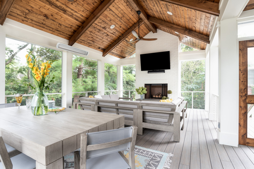 Réalisation d'un grand porche d'entrée de maison arrière tradition avec une cheminée, une terrasse en bois et une extension de toiture.