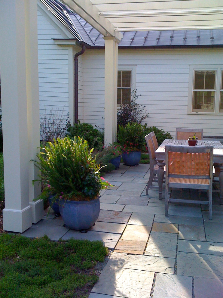 This is an example of a large traditional stone porch design in Richmond with a pergola.