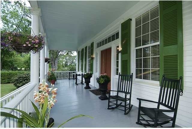 Exempel på en stor klassisk veranda framför huset, med utekrukor, trädäck och takförlängning