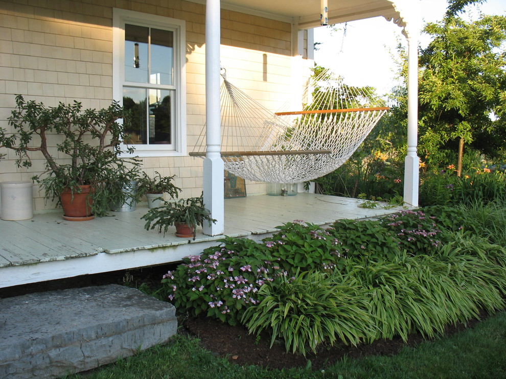 Inredning av en klassisk liten veranda framför huset, med trädäck och takförlängning