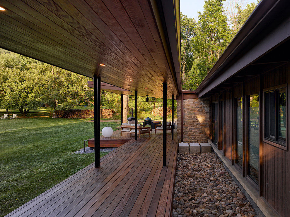 Idee per un grande portico minimalista dietro casa con pavimentazioni in pietra naturale e un tetto a sbalzo