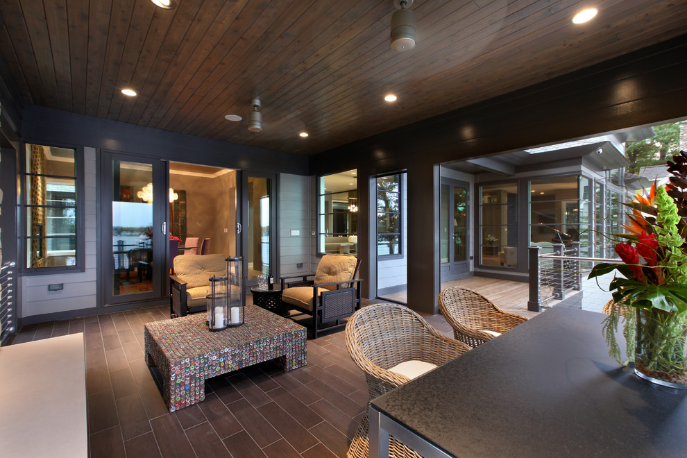 Inspiration pour un grand porche d'entrée de maison arrière design avec un foyer extérieur, du carrelage et une extension de toiture.