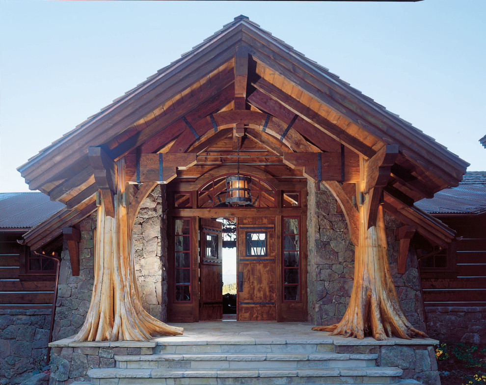 Inspiration för rustika verandor framför huset, med naturstensplattor och takförlängning