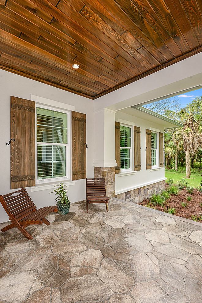 This is an example of a transitional concrete paver porch design in Tampa with a roof extension.