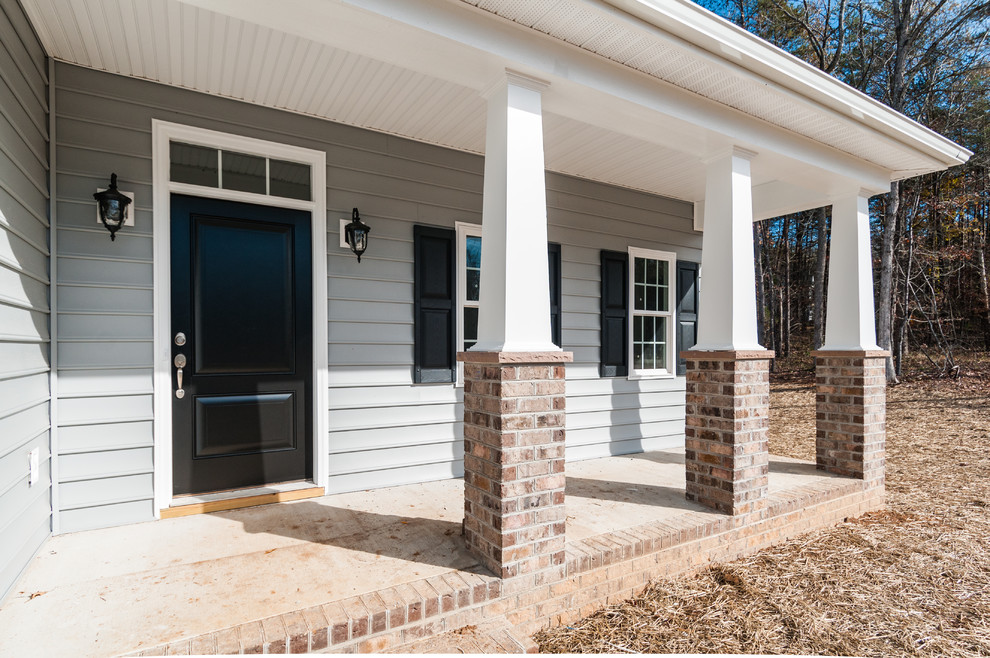 Foto di un piccolo portico stile americano davanti casa con pavimentazioni in mattoni e un tetto a sbalzo