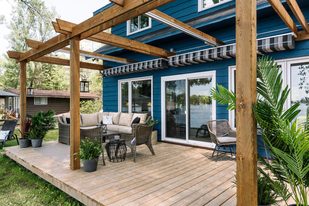 Idées déco pour un porche d'entrée de maison arrière bord de mer avec une terrasse en bois et une pergola.