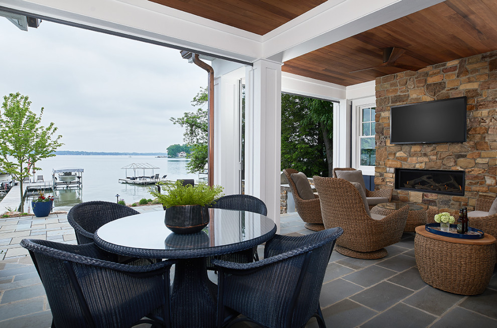 This is an example of a small coastal stone screened-in back porch design in Grand Rapids with a roof extension.