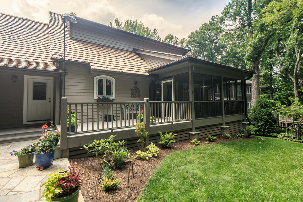 Exemple d'un grand porche d'entrée de maison arrière nature avec une moustiquaire, une terrasse en bois et une extension de toiture.
