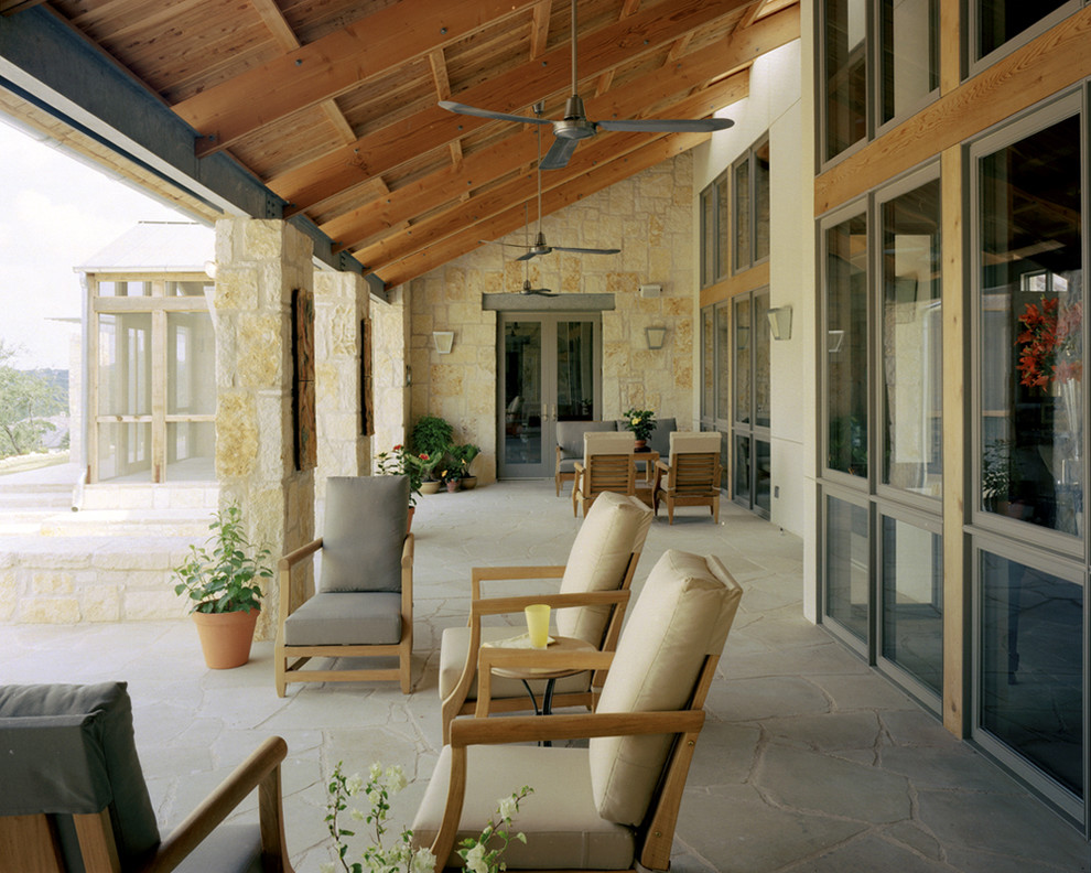 Tuscan stone porch photo in Austin with a roof extension