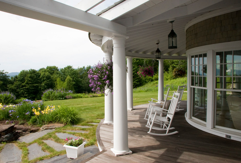 Cette photo montre un grand porche d'entrée de maison avant bord de mer avec une terrasse en bois et une extension de toiture.
