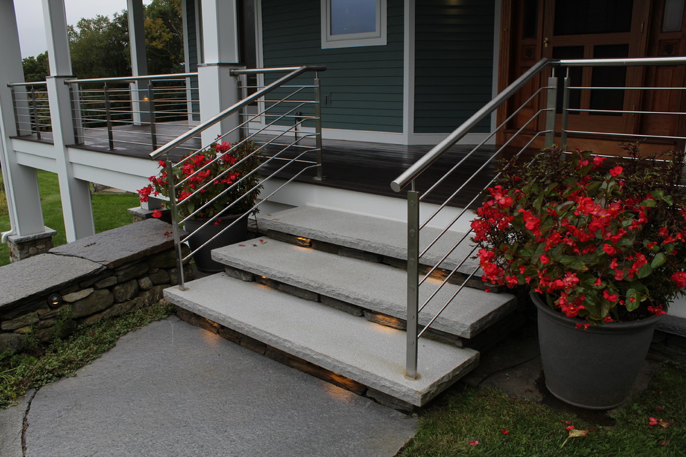 This is an example of a mid-sized contemporary stone front porch design in Boston with a roof extension.
